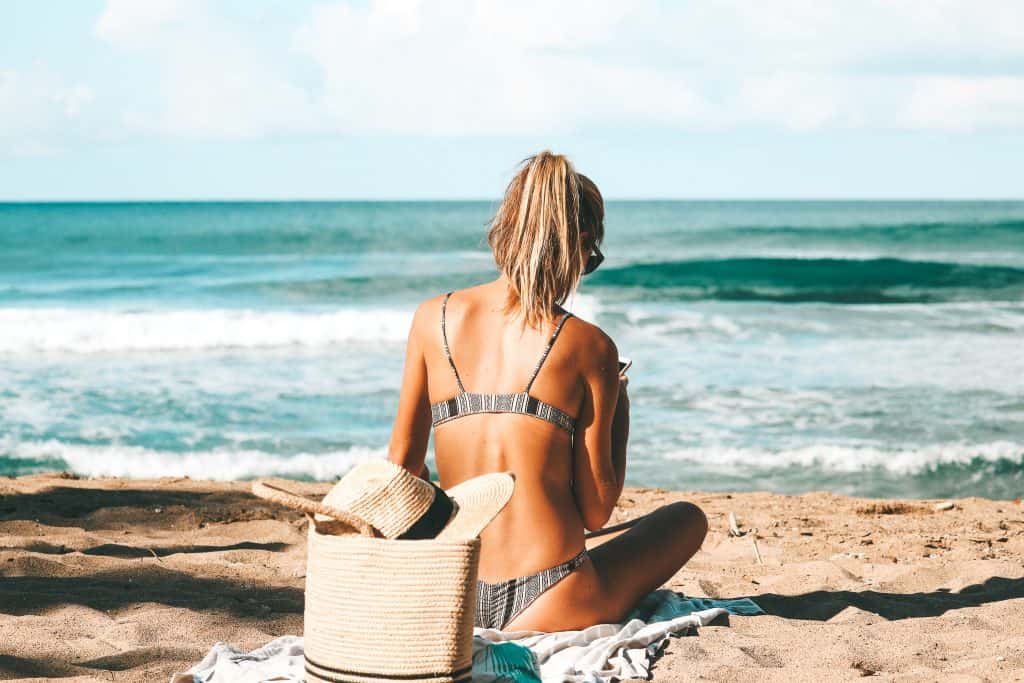 Woman sitting on the beach in a bikini watching the ocean - Rincon, Puerto Rico - beach