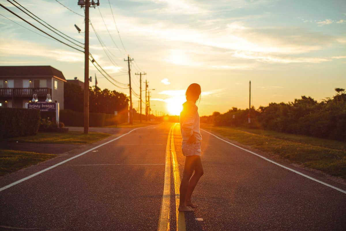 Woman standing in middle of Old Montauk Highway at sunrise
