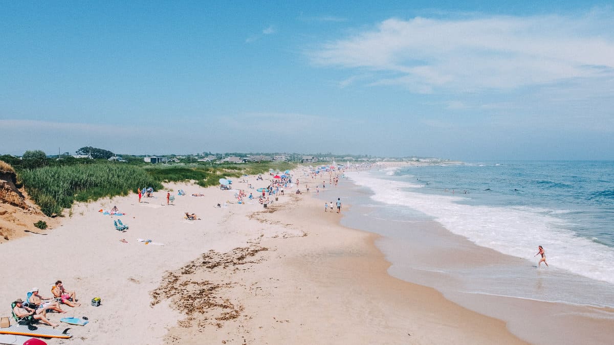 ditch plains beach in summer. ocean sand and dunes with beach goers on beach mid July Montauk NY