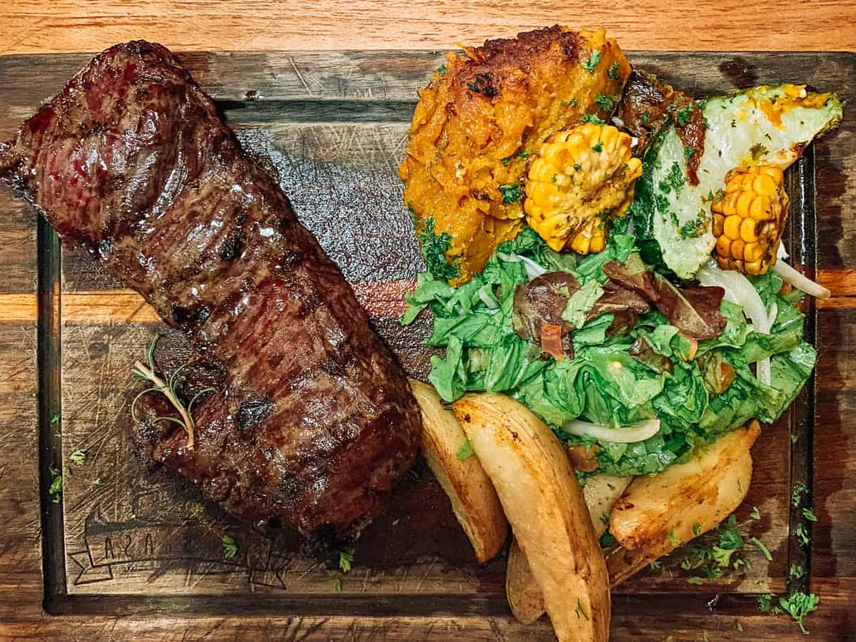 Steak potatos corn and salad on a plate