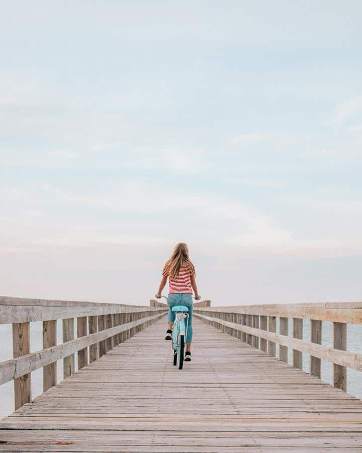 girl wearing red and white striped shirt bike riding down pier