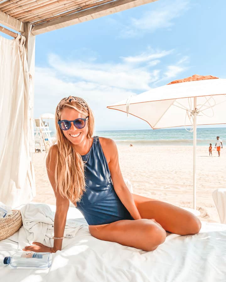 woman wearing black one piece swimsuit at Gurney's Resort cabanas on beach