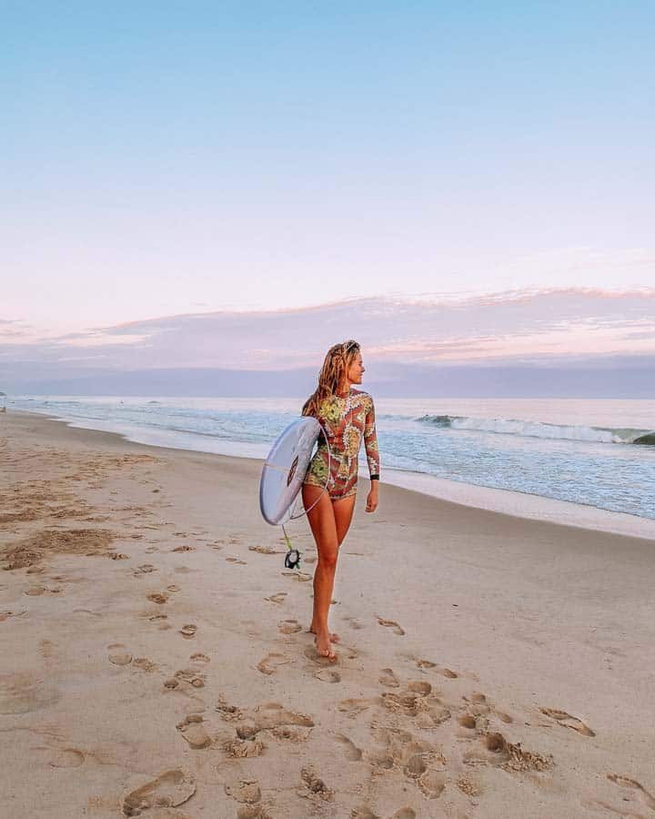 woman holding surfboard on beach in montauk ny