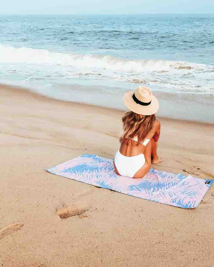 woman wearing beach hat and white bikini sitting on beach in montauk ny
