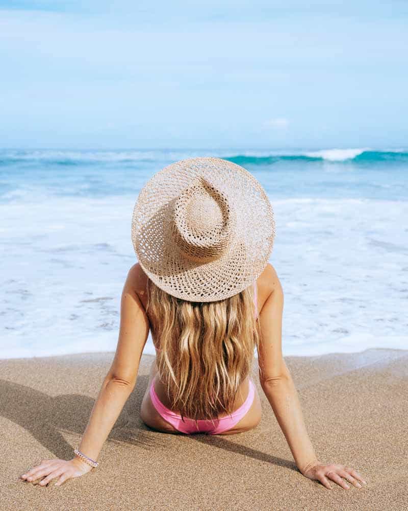 woman sitting in front of ocean in rincon puerto rico with sun hat on