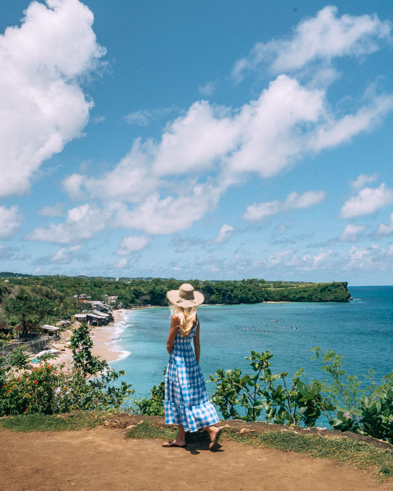 woman in blue and white dress standing at balangan beach view point in bali